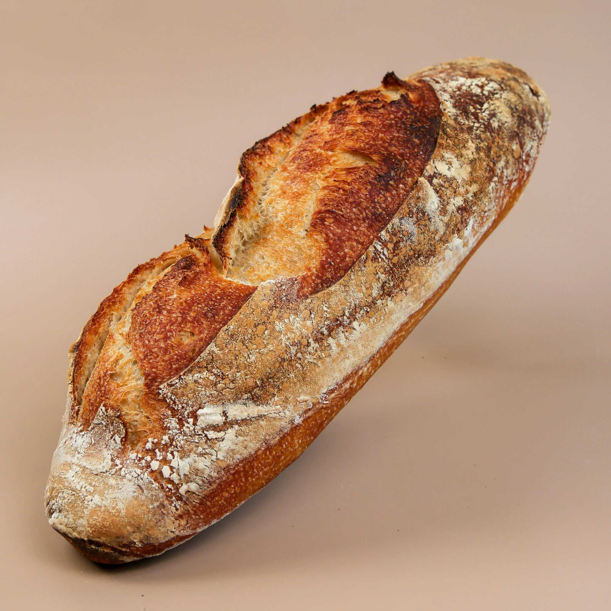 A rustic display of artisanal French bread, including a golden sourdough baguette, seeded loaves, and flaky croissants, highlighting their fresh, handmade quality.