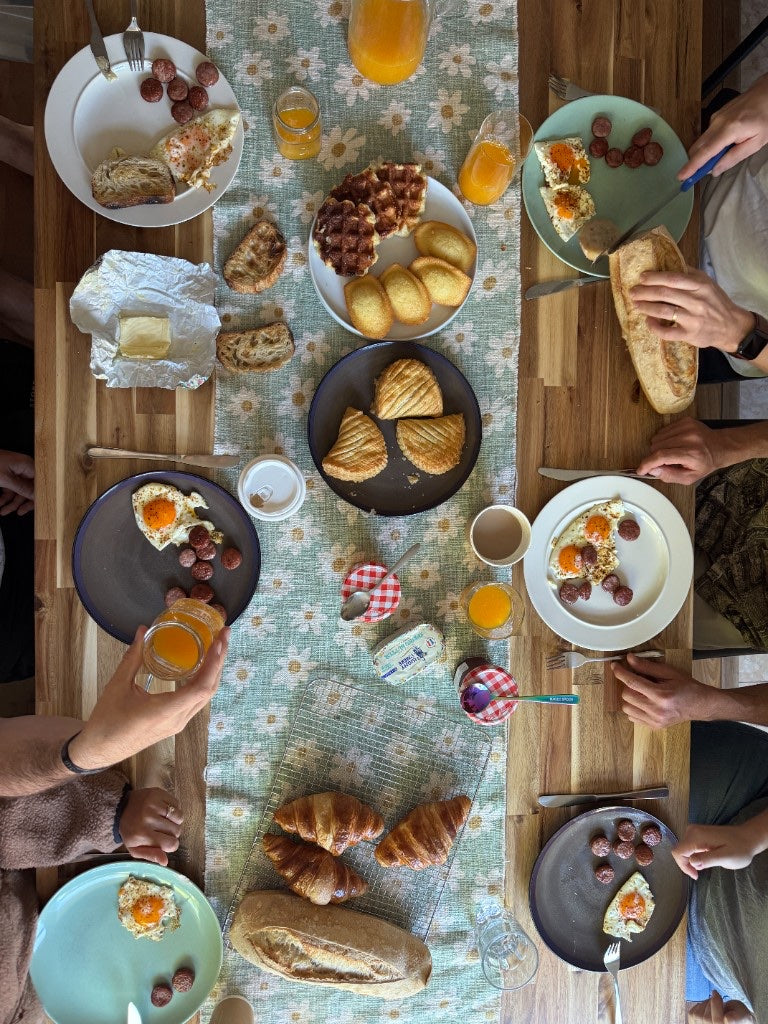 An overhead view of a family breakfast table with croissants and coffee