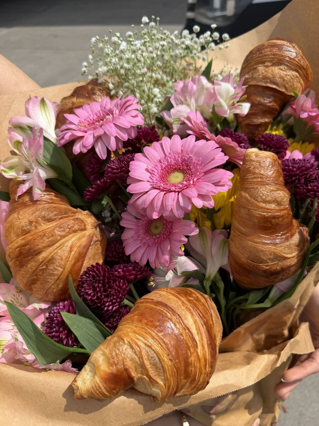 A croissant tucked into a bouquet of pink flowers