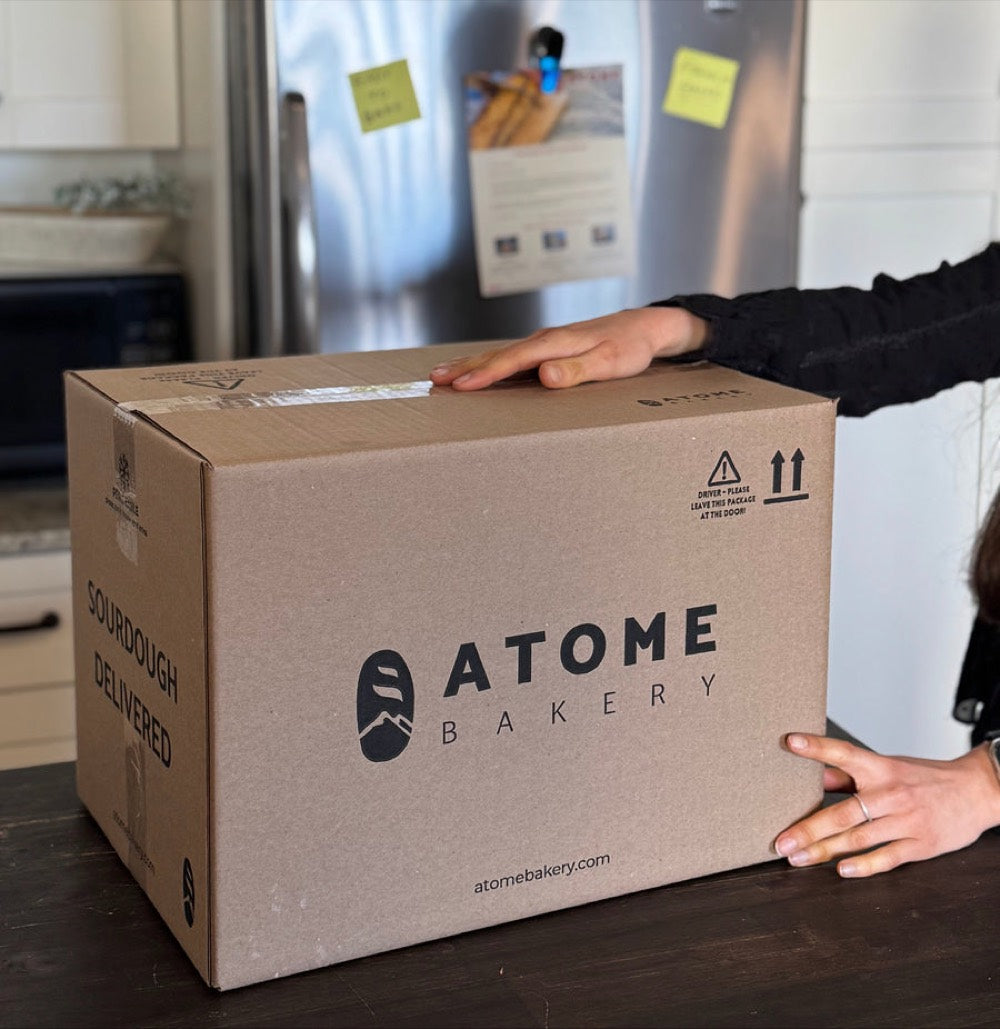 Hands taking a sealed Atome box from a doorstep